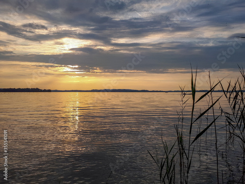 Sunset over the lake Chiemsee in twilight. Scenic view of calm water and sunlight reflections. 