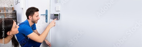 Handyman Installing Security System Near Door Wall