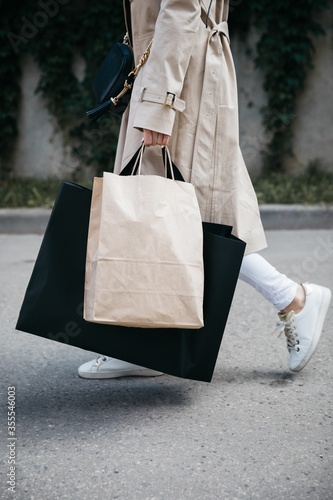 Girl goes after shopping with craft and black bag on the street