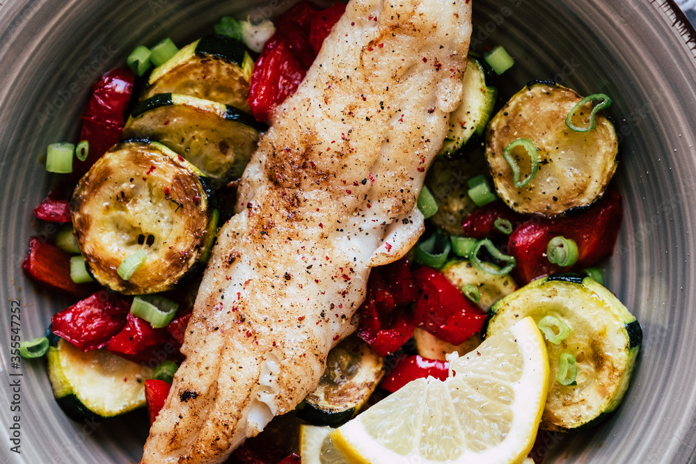 Plat de poisson filet de colin accompagné de légumes courgettes poivrons citron frais