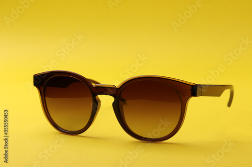 a pair of female or male sunglasses as the means of sun protection or fashionable accessories on yellow background