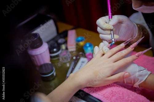 Woman in a nail salon receiving a manicure by a beautician . Manicure process in beautiful salon . Closeup of Woman applying nail varnish to finger nails . Manicure hands salon . photo