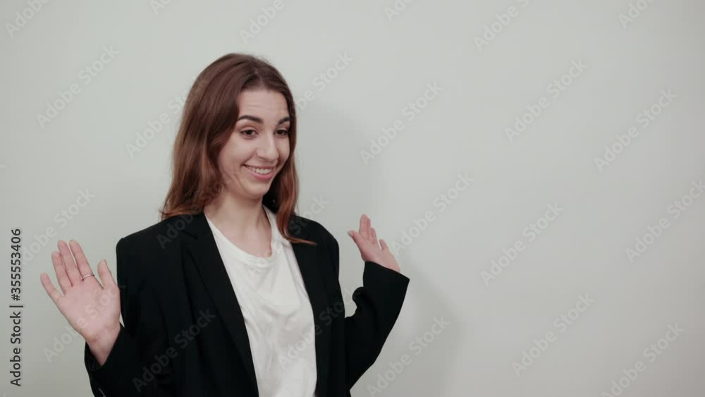 Young attractive woman with brown hair in a light t-shirt and black jacket on white background. Surprised, the woman raised her hands, shows palms. Shocked, puzzled lady Young attractive woman with brown hair in a light t-shirt and black jacket on white background. Surprised, the woman raised her hands, shows palms. Shocked, puzzled lady