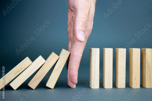 Businessman hand stopped wood blocks. Business risk management concept, businessman protects the fall of the wooden block to planning and strategy at risk for a business alternative and prevents. 