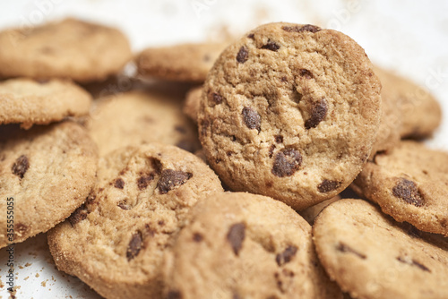 Group of chocolate chip cookies and crumbs on beige background