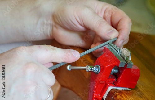 A person making a wrench and a nut with a rasp. Adjust the balance of the nut in the workshop. Repair worker.