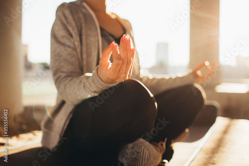 Yogi woman doing sitting in lotus position with a urban view under the bridge. Slim fit girl stretching outside on a sunset. Yoga, fitness, wellness concept. photo