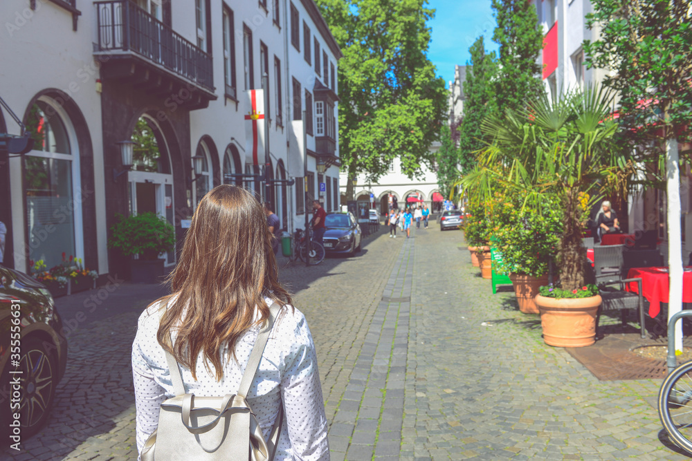 Fototapeta premium Girl In Shirt With Leather Backpack Walk By Old Town Street