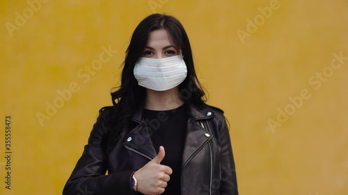 Pretty brunette woman  with mask on the face showing like sign