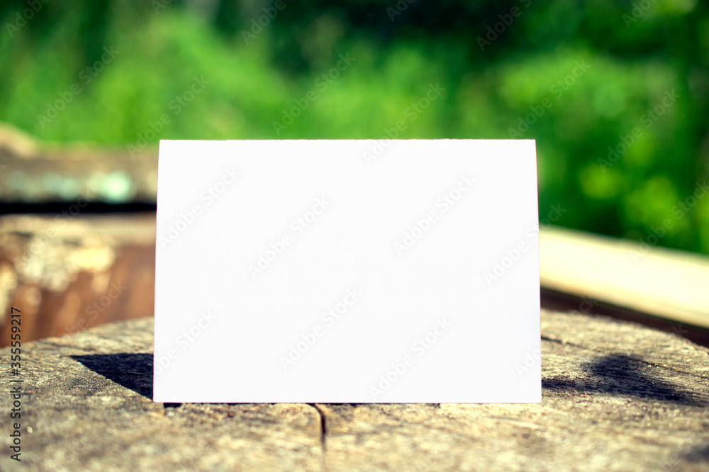 Φωτογραφία Vintage photo of Blank bifold place card on a stump stage and blurred green background behind