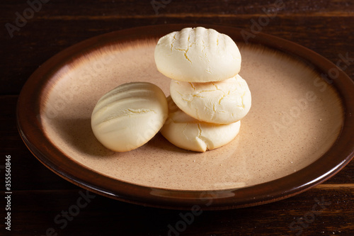 Small round cookies and Cup of coffee in brown dish on wooden table.