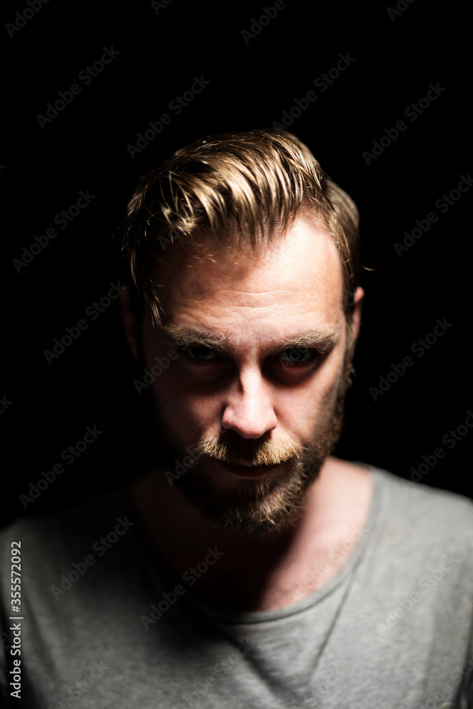 A bearded caucasian male model looking intensely
at the camera wearing a gray shirt