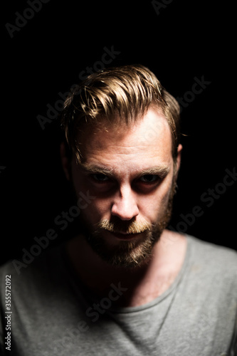 A bearded caucasian male model looking intensely at the camera wearing a gray shirt