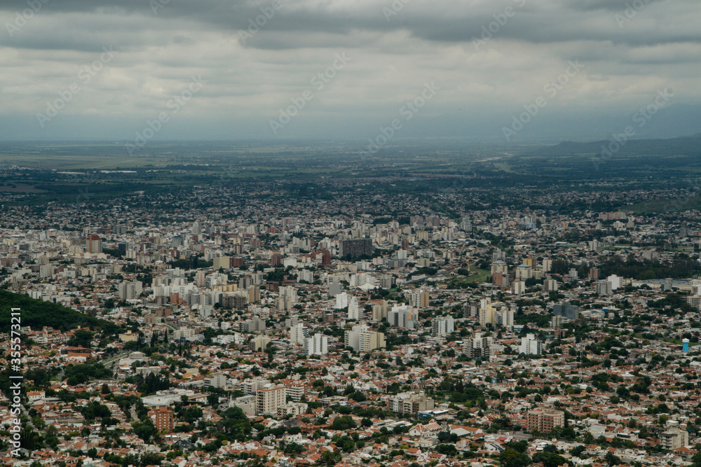 Aerial panorama view of the city Salta, in Argentina, at the foot of the mountains. Many concrete buildings in the valley under a cloudy sky