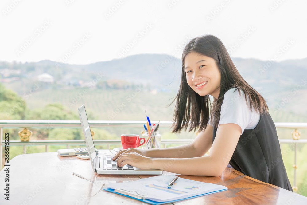 Happy woman sitting by the table while using laptop
