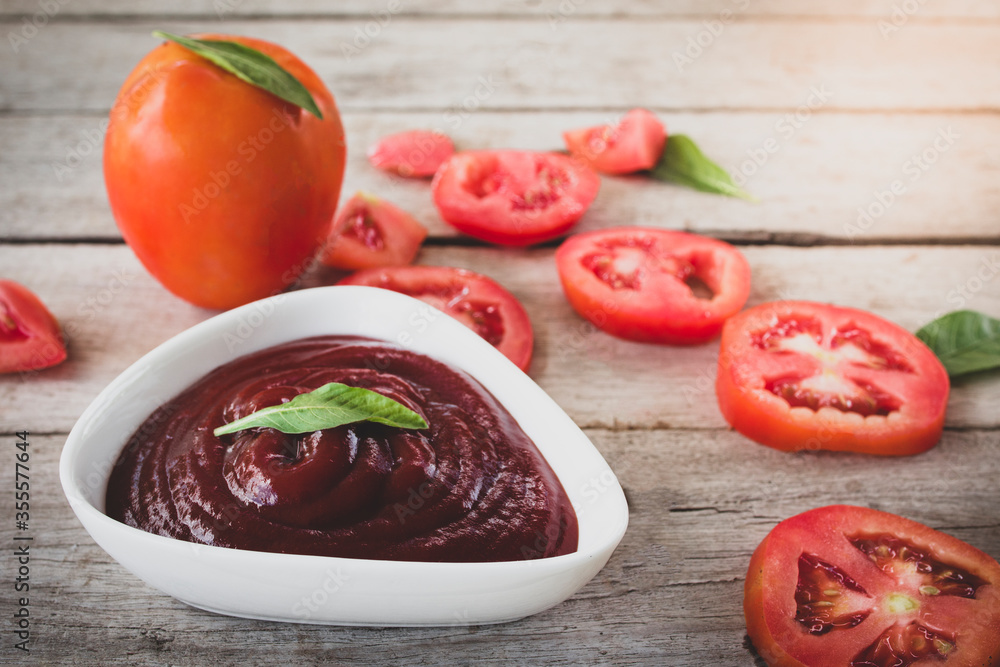 bowl of ketchup or tomato sauce and fresh tomatoes on Wooden table. bowl of ketchup or tomato sauce and fresh tomatoes on Wooden table.