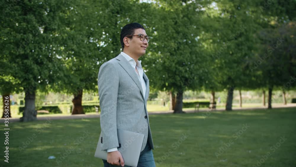 Tracking Shot of a Businessman in Glasses Walking through Park. Tracking Shot of a Businessman in Glasses Walking through Park.
