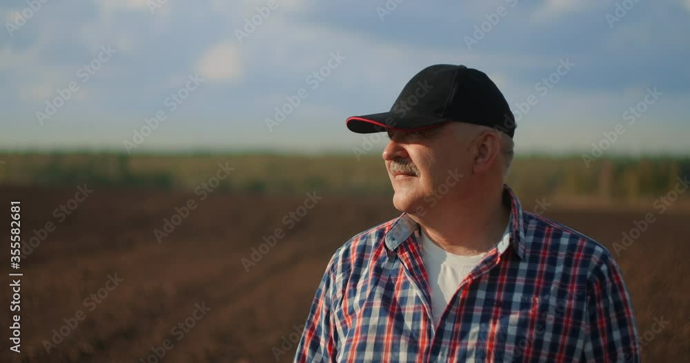 Slow motion A tractor driver looks at the work done at sunset Slow motion A tractor driver looks at the work done at sunset