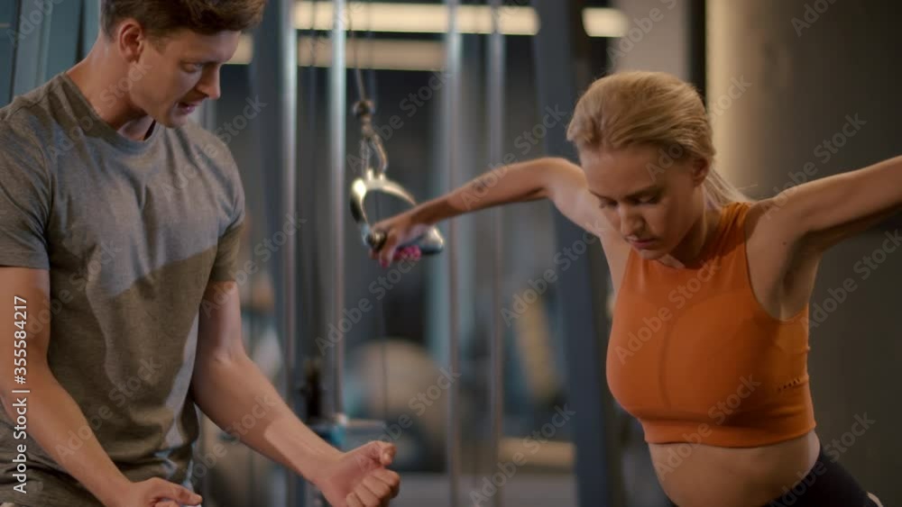 Sporty couple training in fitness center. Fit girl making arm curls at gym Sporty couple training in fitness center. Fit girl making arm curls at gym