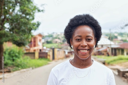 a young african lady with afro hair smiling and looking at the camera