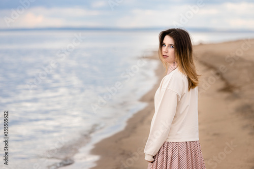 A young beautiful girl walks along the shore and looks back.