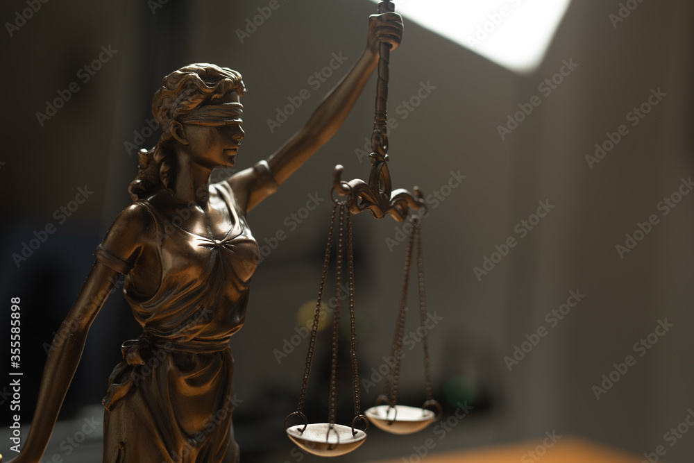 Scales of Justice, Justitia, Lady Justice and Law books in the background..