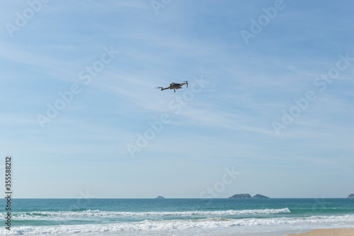 Drone flying in blue sky with clouds in the background. Drone flying overhead in cloudy blue sky. Drone quad copter with high resolution digital camera on the sky.