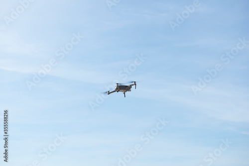 Drone flying in blue sky with clouds in the background. Drone flying overhead in cloudy blue sky. Drone quad copter with high resolution digital camera on the sky.
