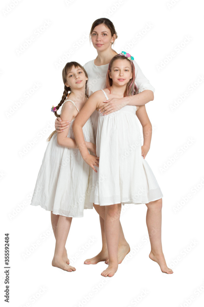 Family mother and two daughters in similar long white dresses.