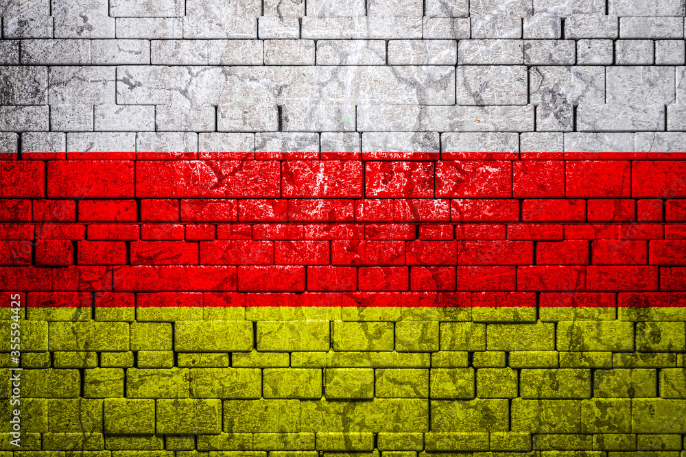 National flag of Ossetia on brick wall background.The concept of national pride and symbol of the country. Flag banner on stone texture background. National flag of Ossetia on brick wall background.The concept of national pride and symbol of the country. Flag banner on stone texture background.