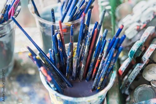 Detail of paintbrushes with a defocused art in the background.