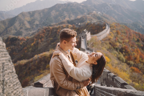 beautiful young couple showing affection on the Great Wall of China. Newly married couple on their honemoon to Great Wall near Beijing China. Stylish couple exploring one of the wonders of the world photo