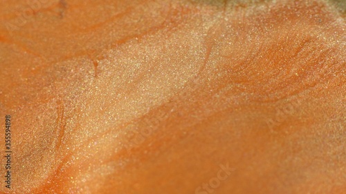 Orange, coral color liquid paint. Cosmetic glitter texture. Abstract background. Hypnotic mixing and movement of the ink