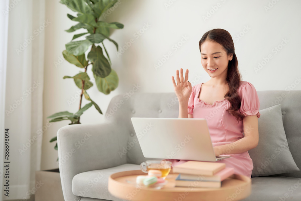 Young Asian woman calling her friend by laptop at living room. Young Asian woman calling her friend by laptop at living room.