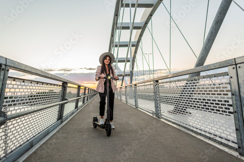A young girl standing on the bridge next to her electric scooter © MexChriss
