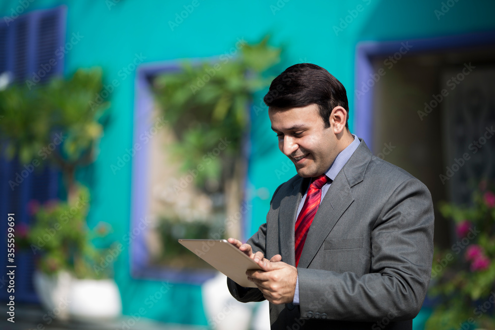 Young businessman doing work on tablet outside of an office building. Young businessman doing work on tablet outside of an office building.