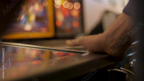 Close-up on a man's hands getting frustrated while playing pinball at an arcade