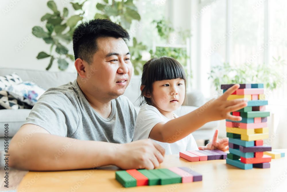 Fototapeta premium Asian father and daughter are doing puzzle game
