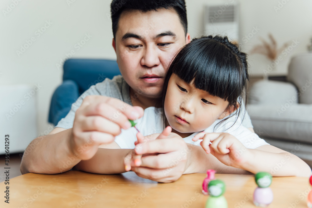 Asian father and daughter are applying nail polish