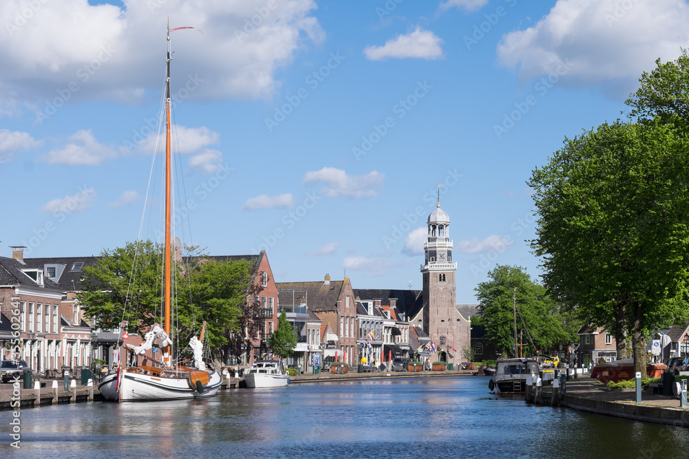 Yachts in the port of Lemmer in spring with reformed Church in Friesland, Netherlands