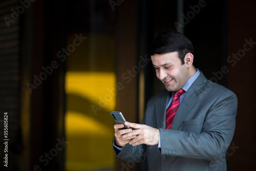 Smiling businessman with smart phone outdoors on the street, with copy space.New lower prices High-quality images for all your projects ₹345 for this image ₹170 with a 1-month subscription 10 images