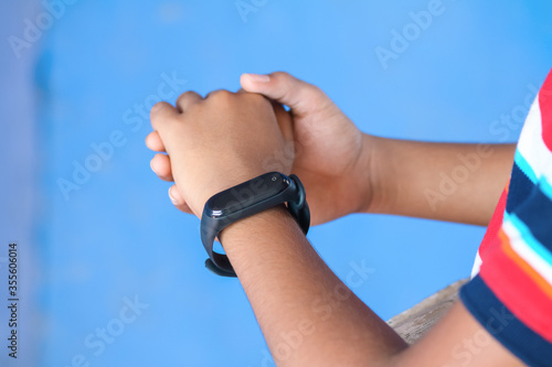 Indian boy wearing smartwatch in his hand  
