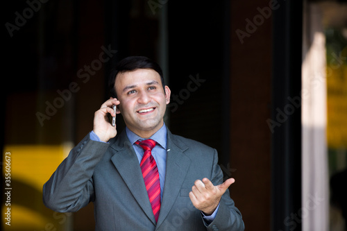 Smiling young businessman calling by mobile phone