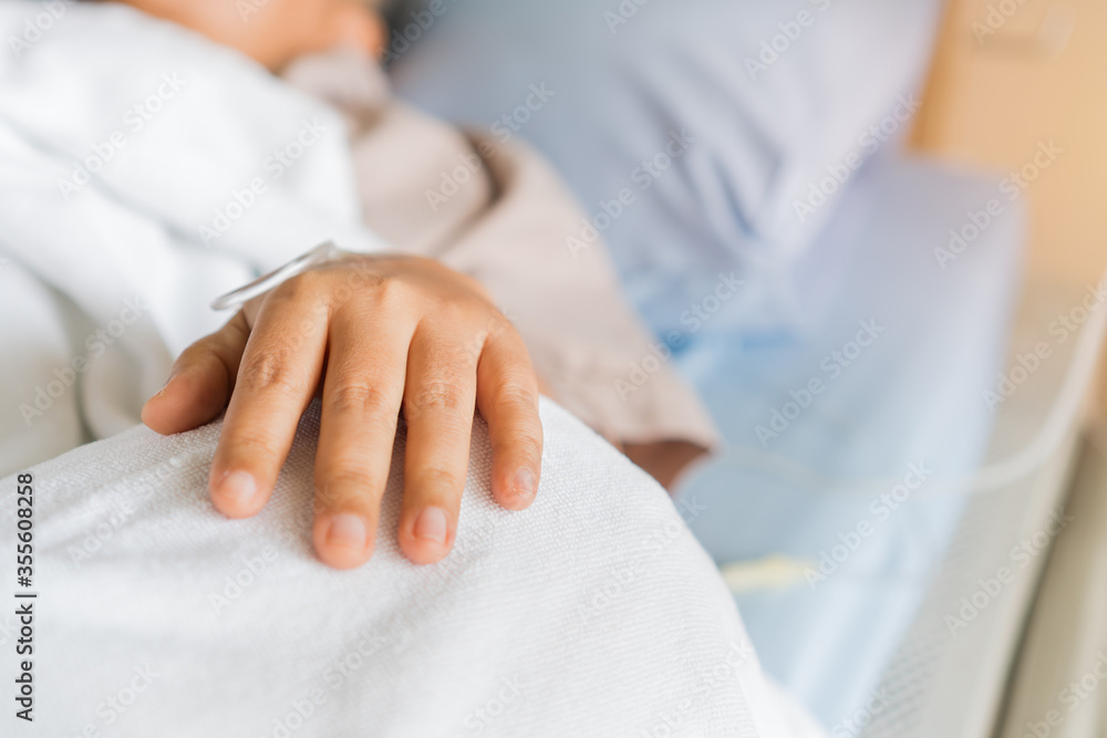 Obraz premium Coronavirus 2019-nCoV virus infection, COVID-19 treatment concept, Healthcare medicine patients saline, Iv drip, hand medical intravenous needle, give salt water on hospital bed.intravenous therapy