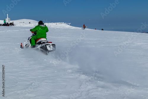 Rider on the snowmobile in the mountains ski resort. A man is riding snowmobile in mountains