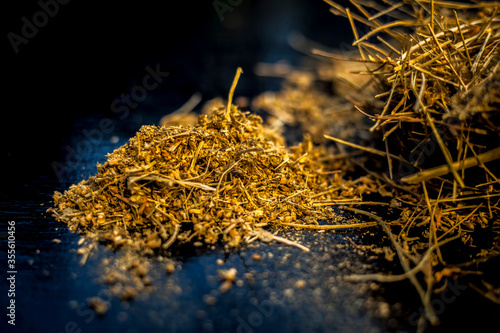 Close up of shankhpushpi roots on wooden surface along with some of its powder with it. Shot with blurred background.