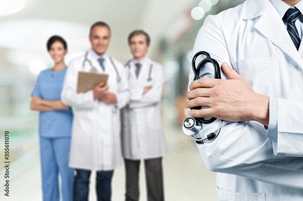 Young man doctor holding stethoscope on hospital background Young man doctor holding stethoscope on hospital background