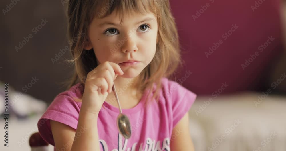 Adorable little girl in the sunlit living room watching tv and eating cereals Adorable little girl in the sunlit living room watching tv and eating cereals