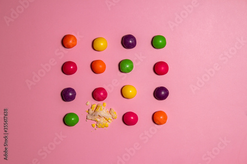 Broken candy among whole ones on color background. Concept of uniqueness