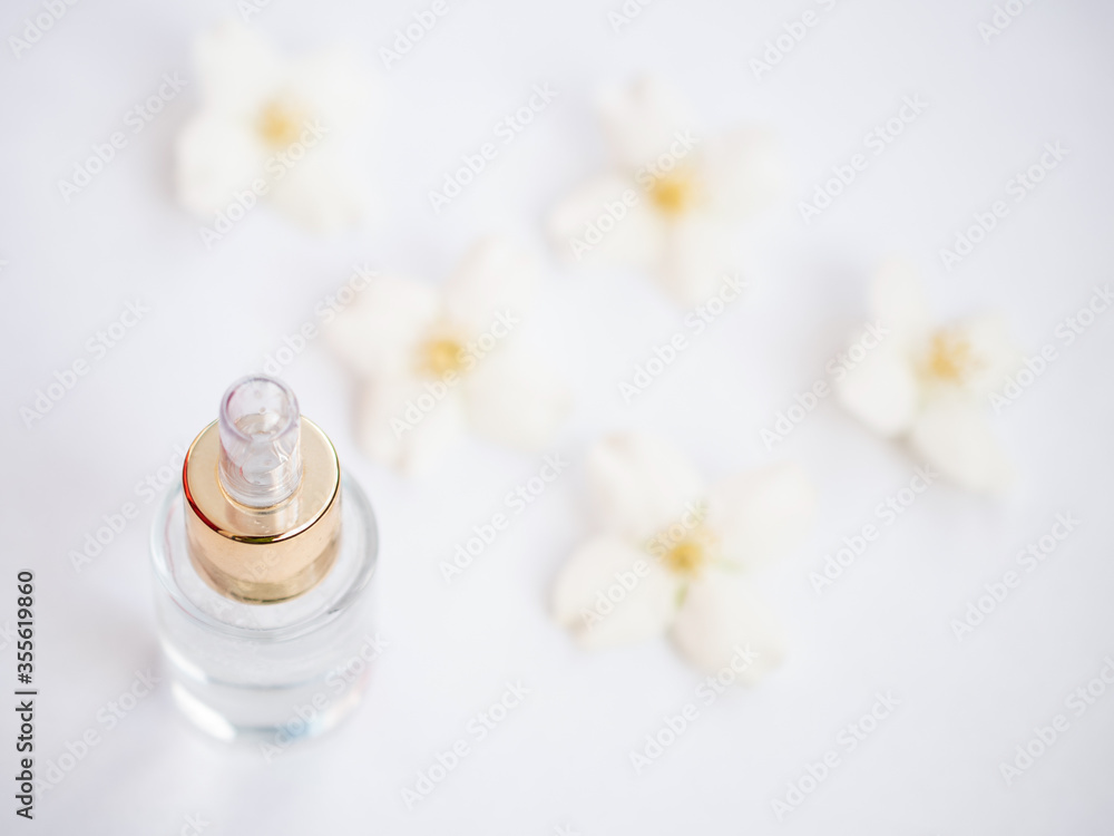 Jasmine essential oil (tincture, remedy, infusion). Glass bottle with fresh jasmine flowers on a white background. Flower essential oil. Phytotherapy. View from above Jasmine essential oil (tincture, remedy, infusion). Glass bottle with fresh jasmine flowers on a white background. Flower essential oil. Phytotherapy. View from above
